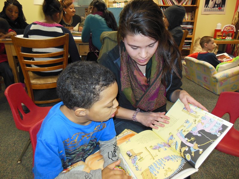 A teenaged her and young boy reading a children's book together.